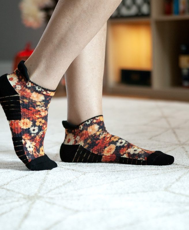 Stepping across a white rug in orange and black floral ankle compression socks