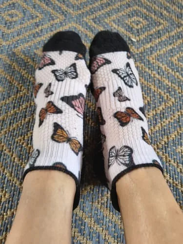 White butterfly-pattern Ankle Compression socks worn on a woven rug