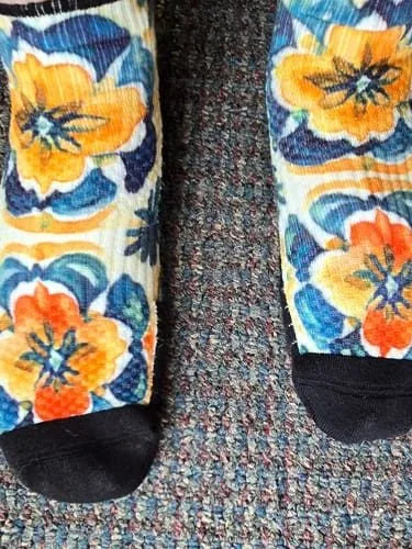 Orange pansy-pattern Ankle Compression socks worn standing on a patterned rug