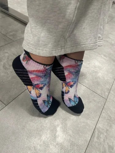 Pastel butterfly-pattern Ankle Compression socks worn standing on a tile floor