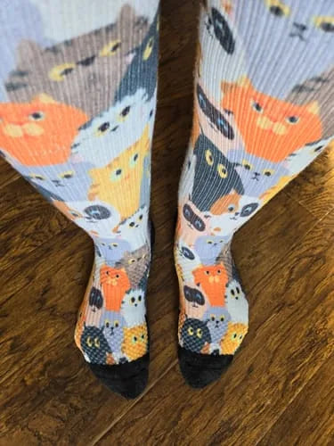 Orange cat-pattern Compression socks worn standing on a wood floor