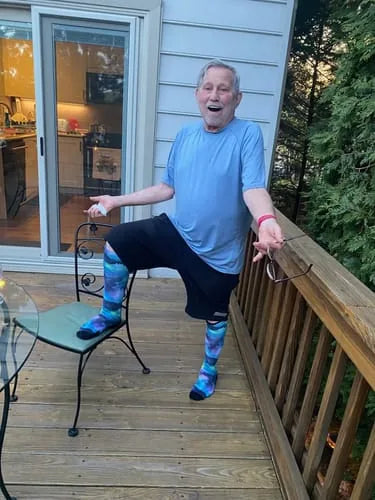 Man in blue patterned Compression socks standing on a deck