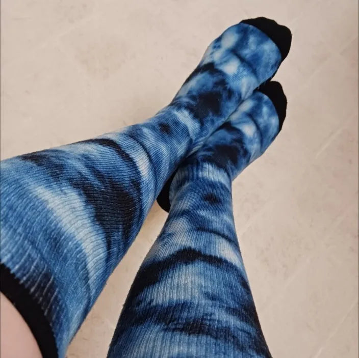 Blue tie-dye Compression socks worn with legs crossed on a floor