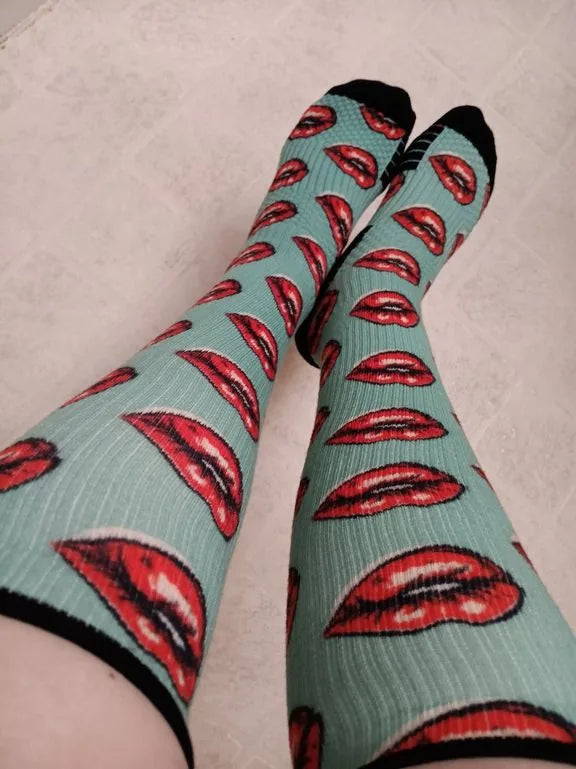 Green lip-pattern Compression socks worn with legs up on a tile floor
