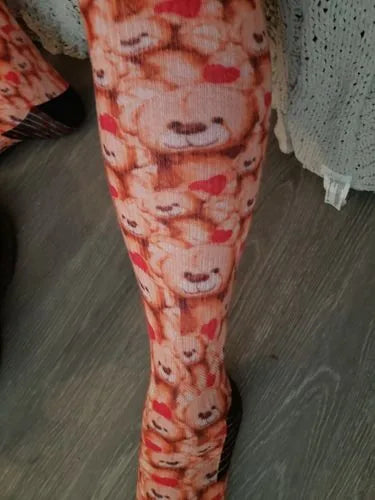 Red and orange teddy-bear-pattern Compression socks worn standing at home