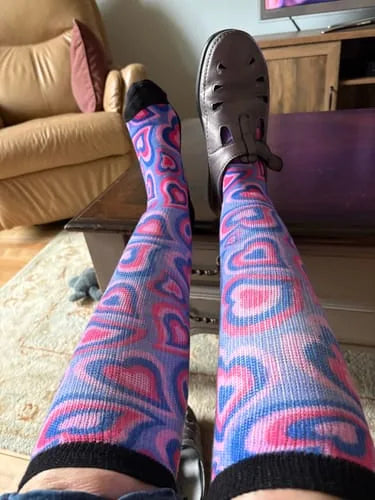 Pink and blue heart-pattern EasyStretch™ socks worn with legs crossed