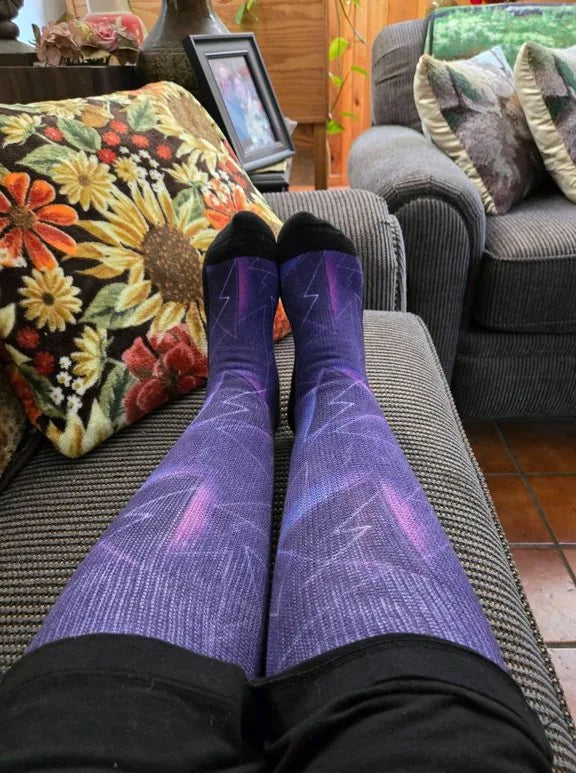 Purple lightning-pattern EasyStretch™ socks worn with legs up on a sofa