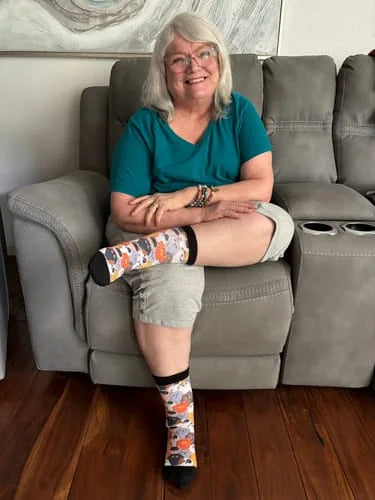 Woman smiling in colourful EasyStretch™ socks on a sofa