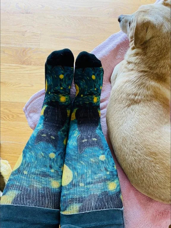 Starry-night cat-pattern EasyStretch™ socks worn with feet up beside a dog