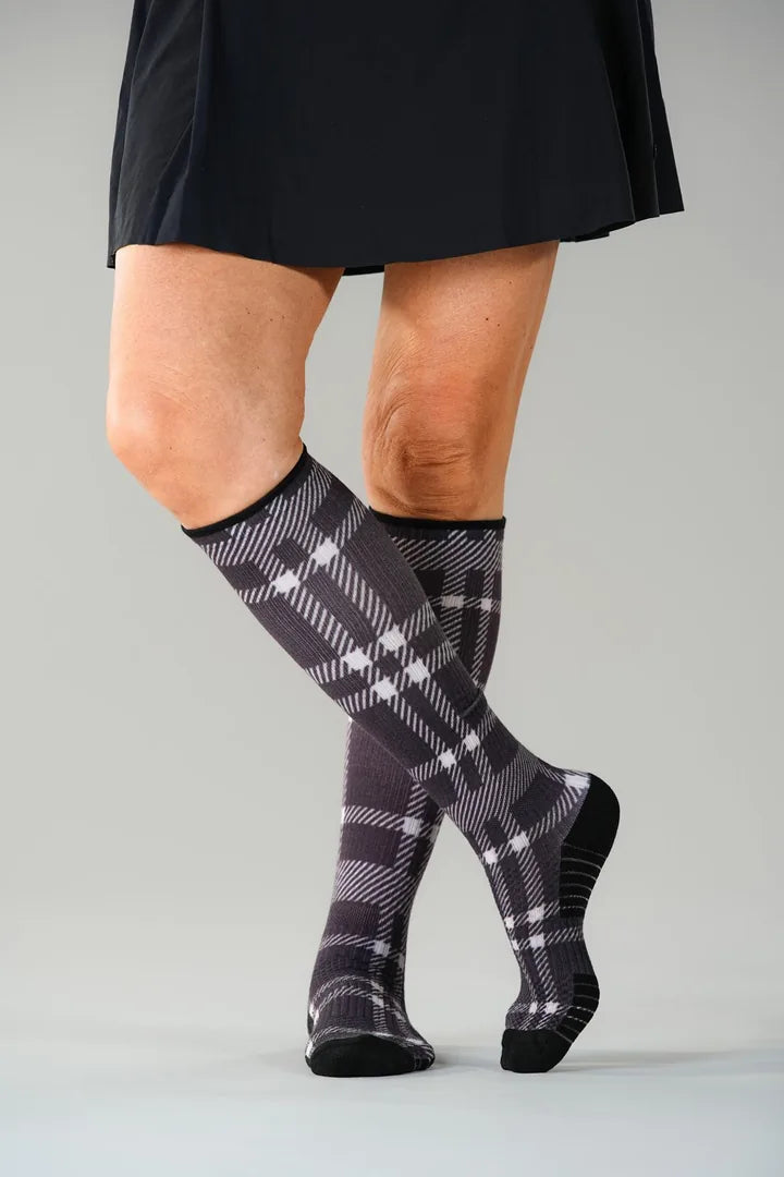 Chocolate Plaid Compression socks worn standing, legs crossed, ending just below the knee